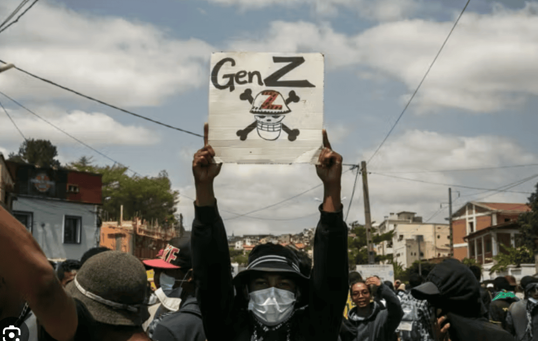 Un jeune manifestant brandit une pancarte indiquant son affiliation au mouvement qui mène la lutte. Antananarivo, Madagascar, 27:09:2025 ©AFP - Rijasolo